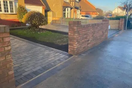 Charcoal block-paved drive beside a new brick front wall