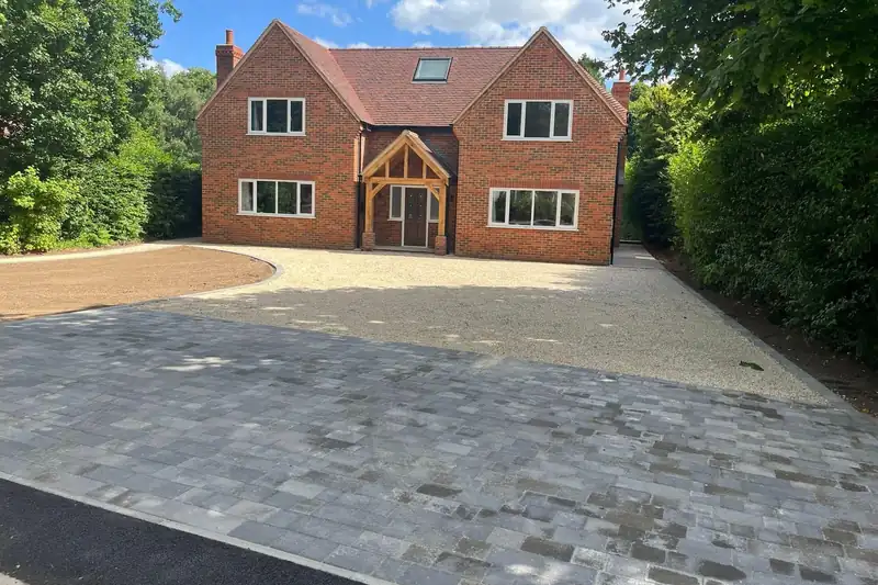New block-paved apron and gravel drive in front of a detached brick house