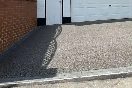 Grey resin driveway in front of a white double garage