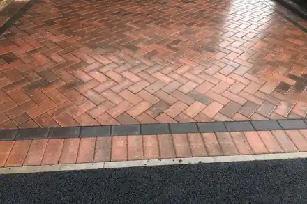Red brindle block paving in a herringbone pattern with a dark edge course